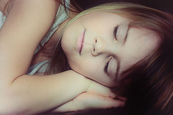 girl laying on her side sleeping with her head resting on her hands