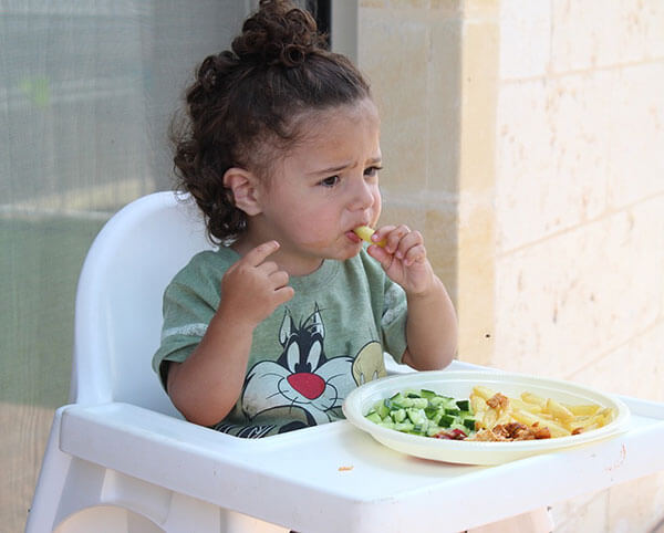 a toddler sitting in a high chair eating food