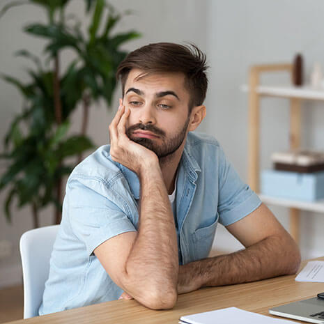 man sitting at desk with chin resting on hand tired