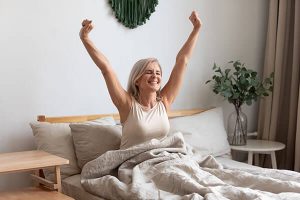 A smiling woman just waking up, stretching her arms over her head