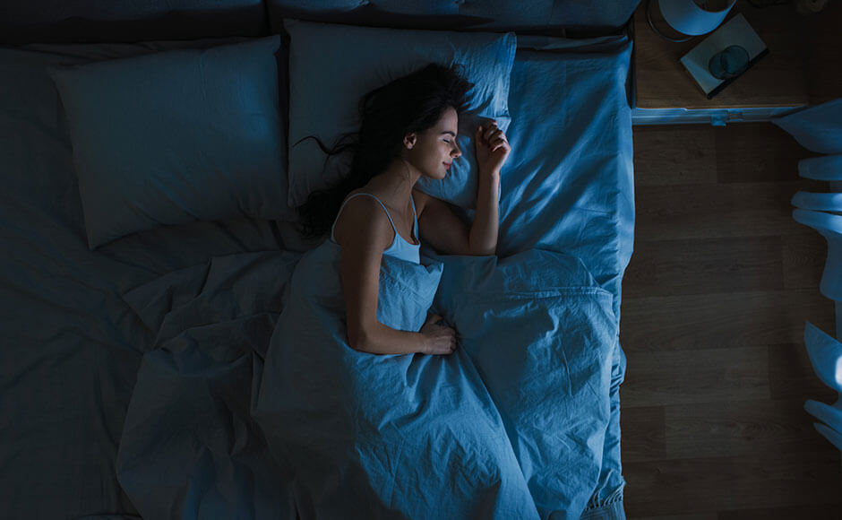 picture from above of a dark-haired woman sleeping on her side in bed